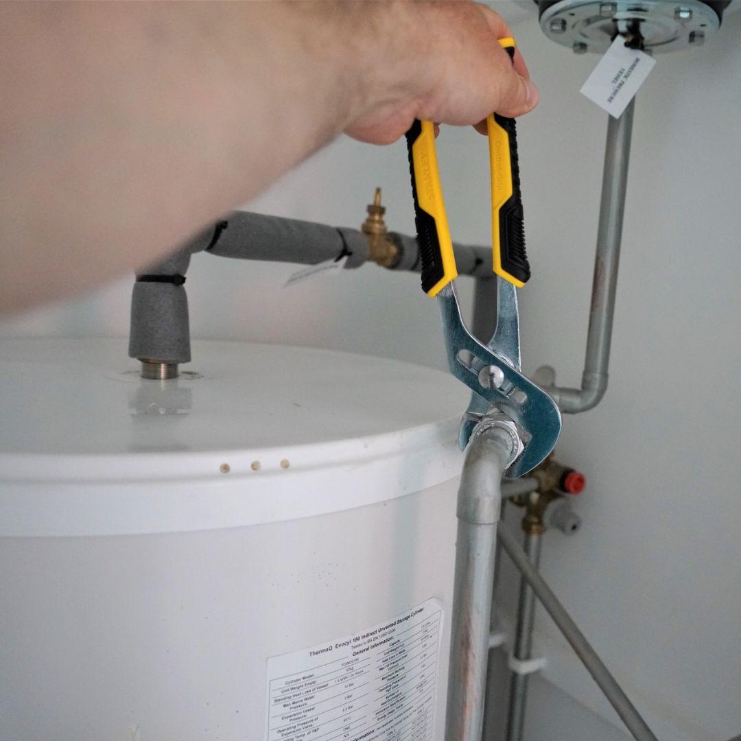 A plumber holds a plier tool for a plumbing repair
